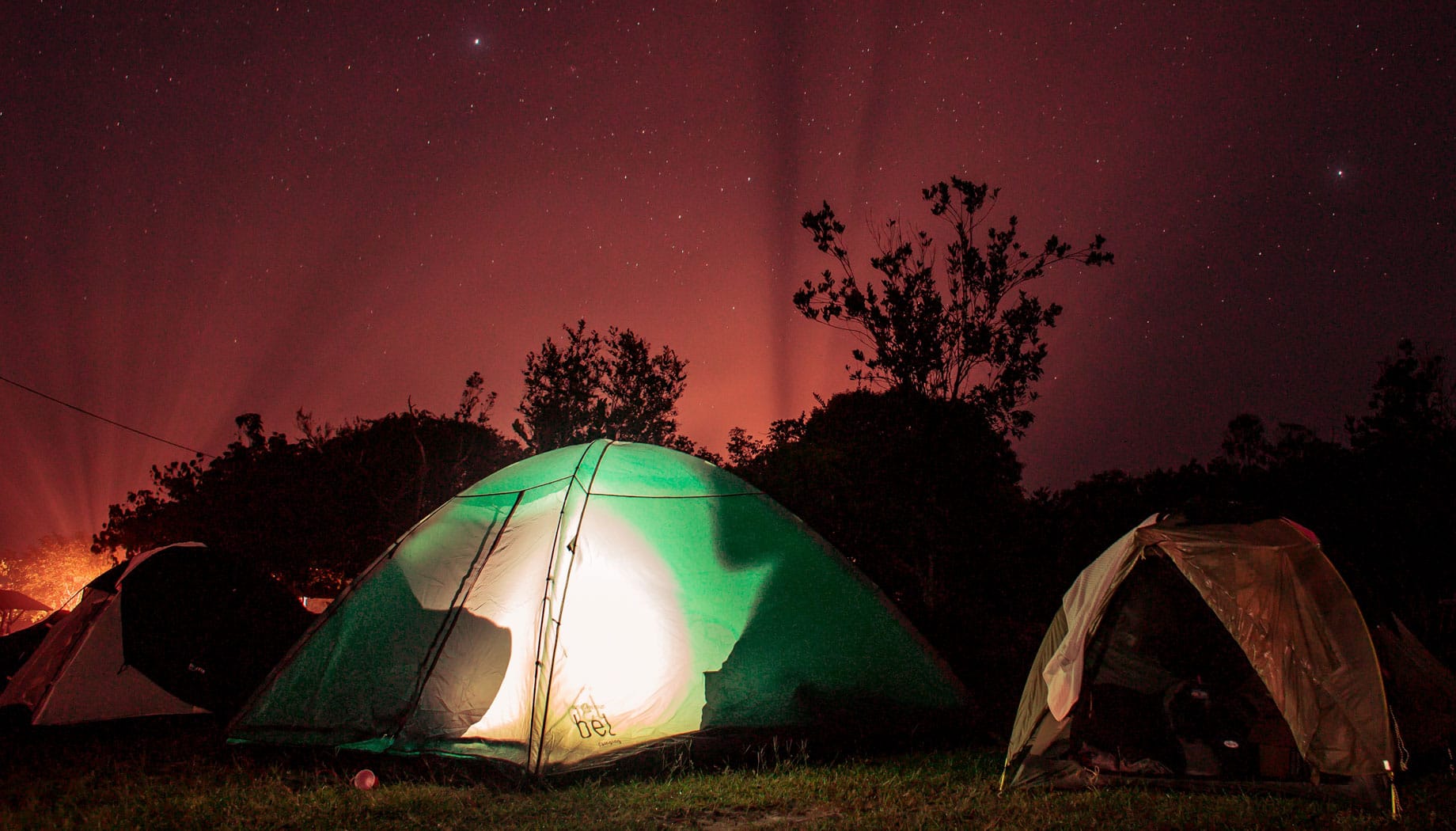 Three tents camping under a bright night sky.