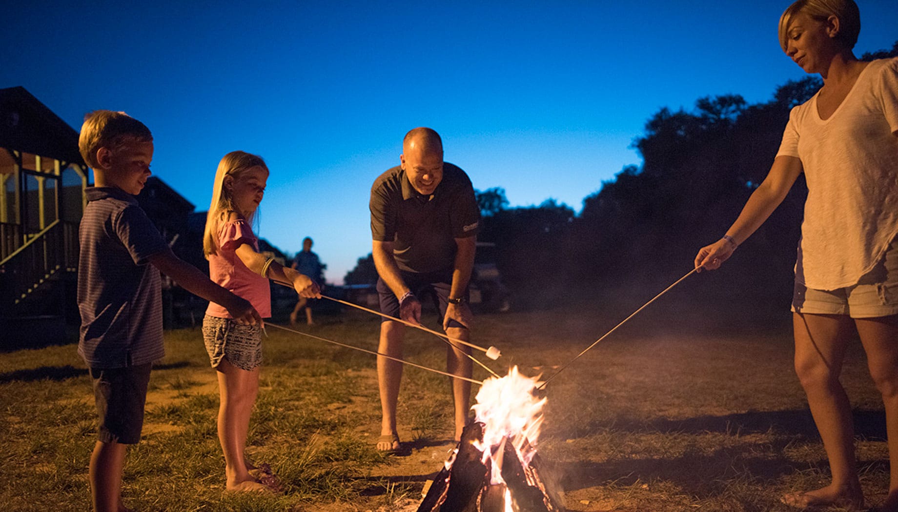 Family toasting marshmallows around a campfire.