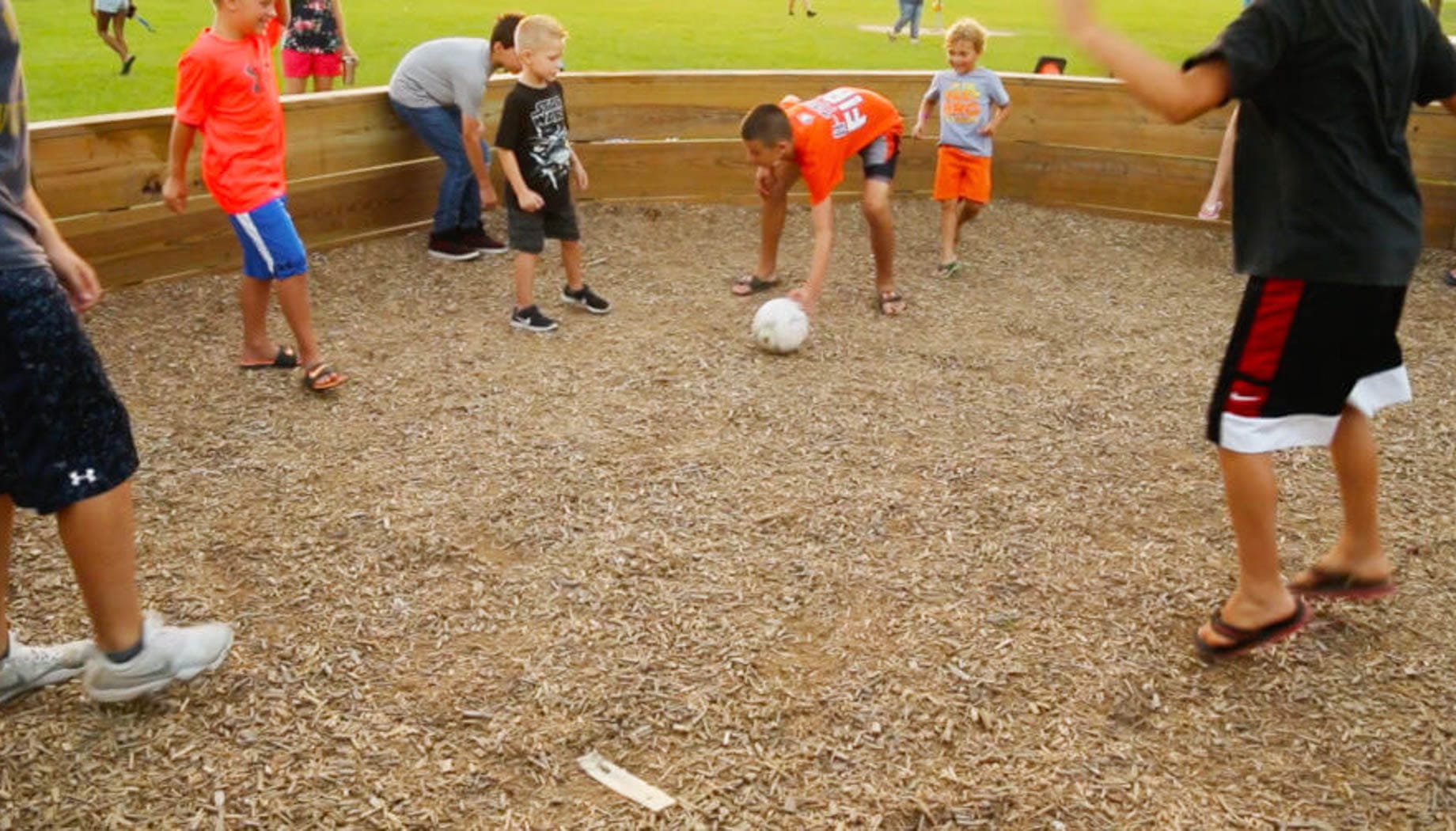 Group of kids playing a game of Gaga Ball in a pit.