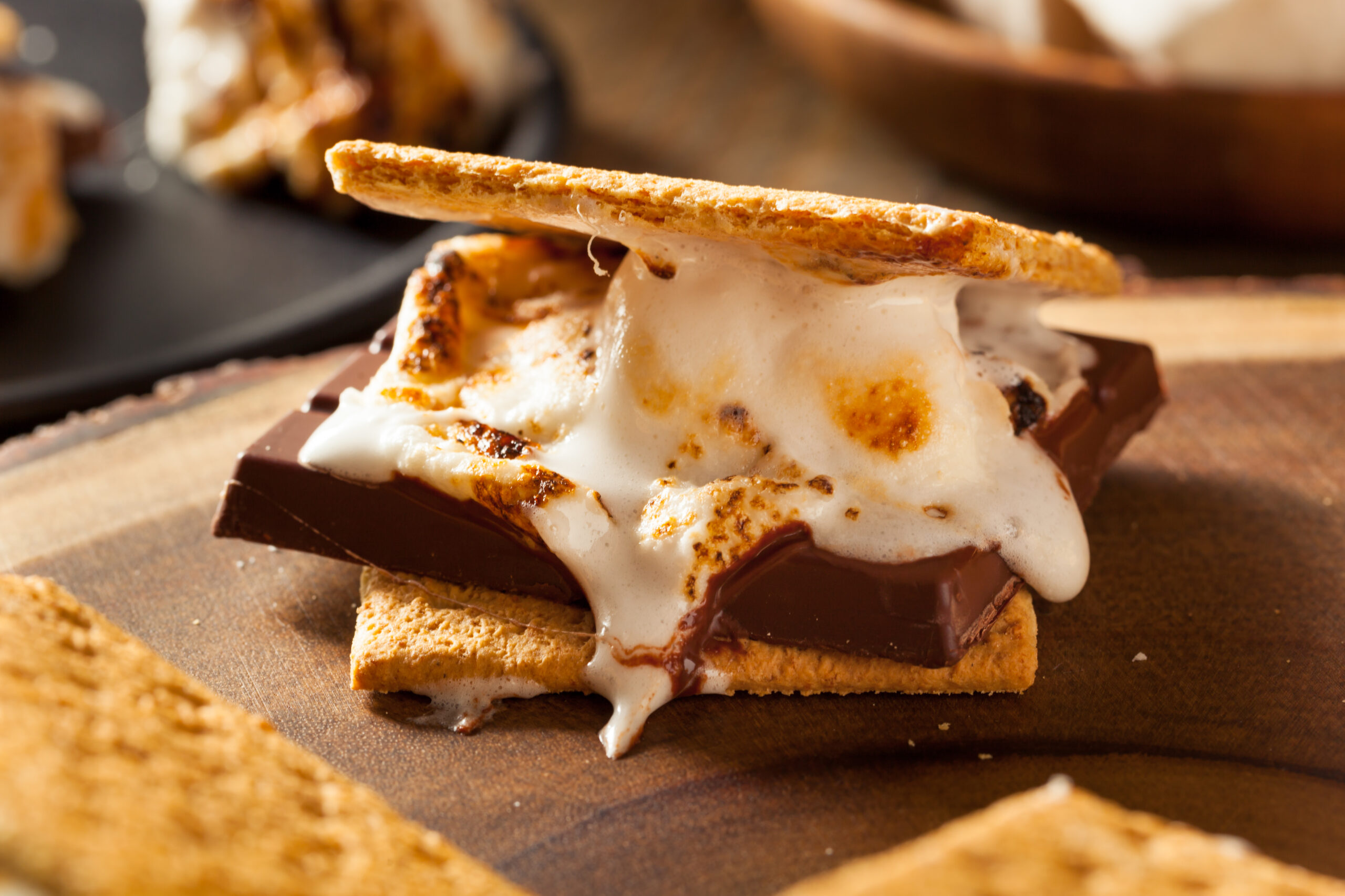 Gooey marshmallow smores on a wooden dish.