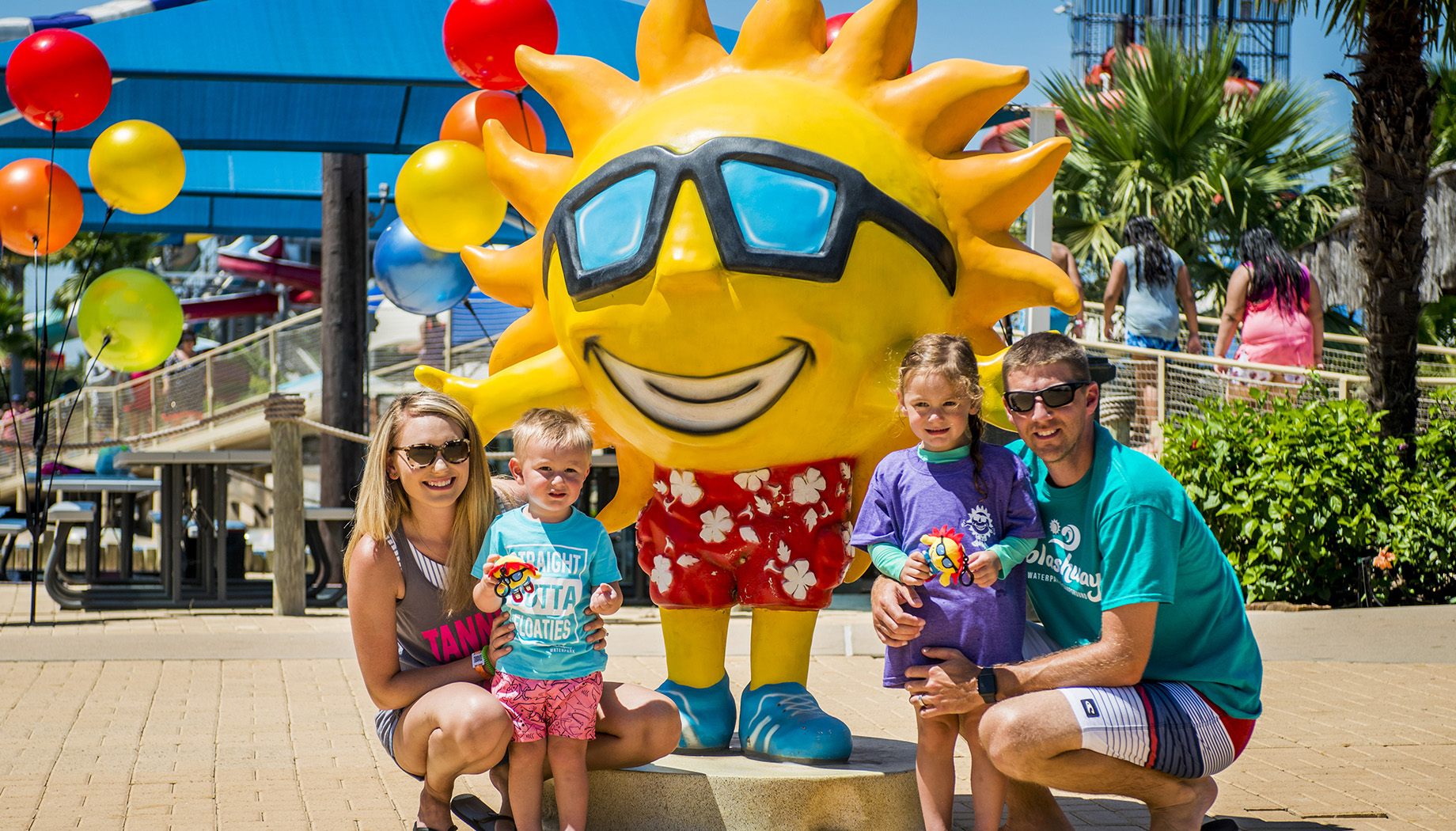 Family posing next to a sculpture of Ray--Splashway's sun mascot.