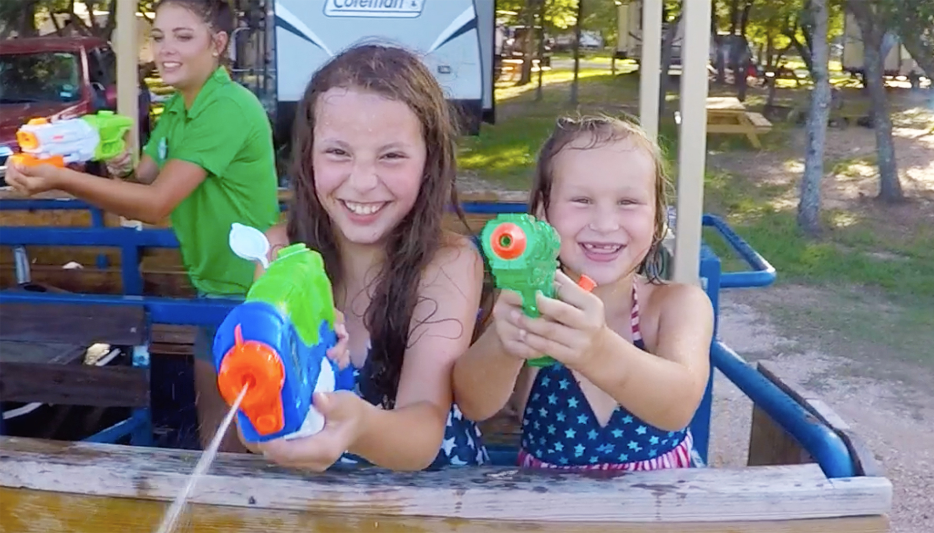 Two girls holding water guns aimed at the camera.