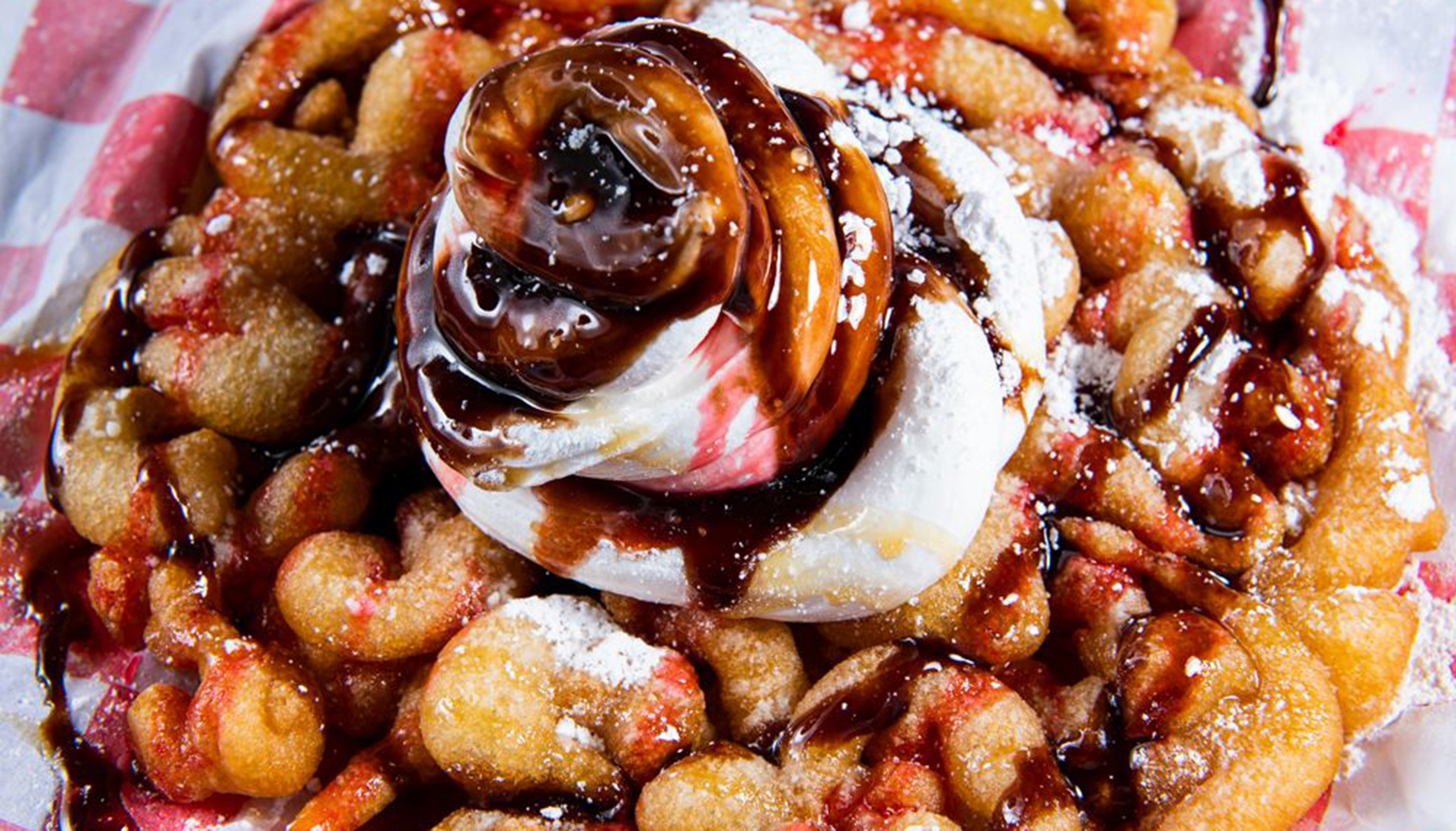 Funnel cake with strawberries, whipped cream, and chocolate drizzle.